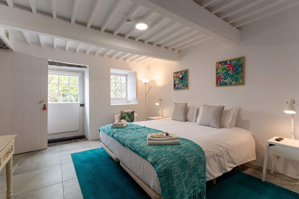 A bedroom with a bed, bedside tables, a window, and artwork on the wall.
