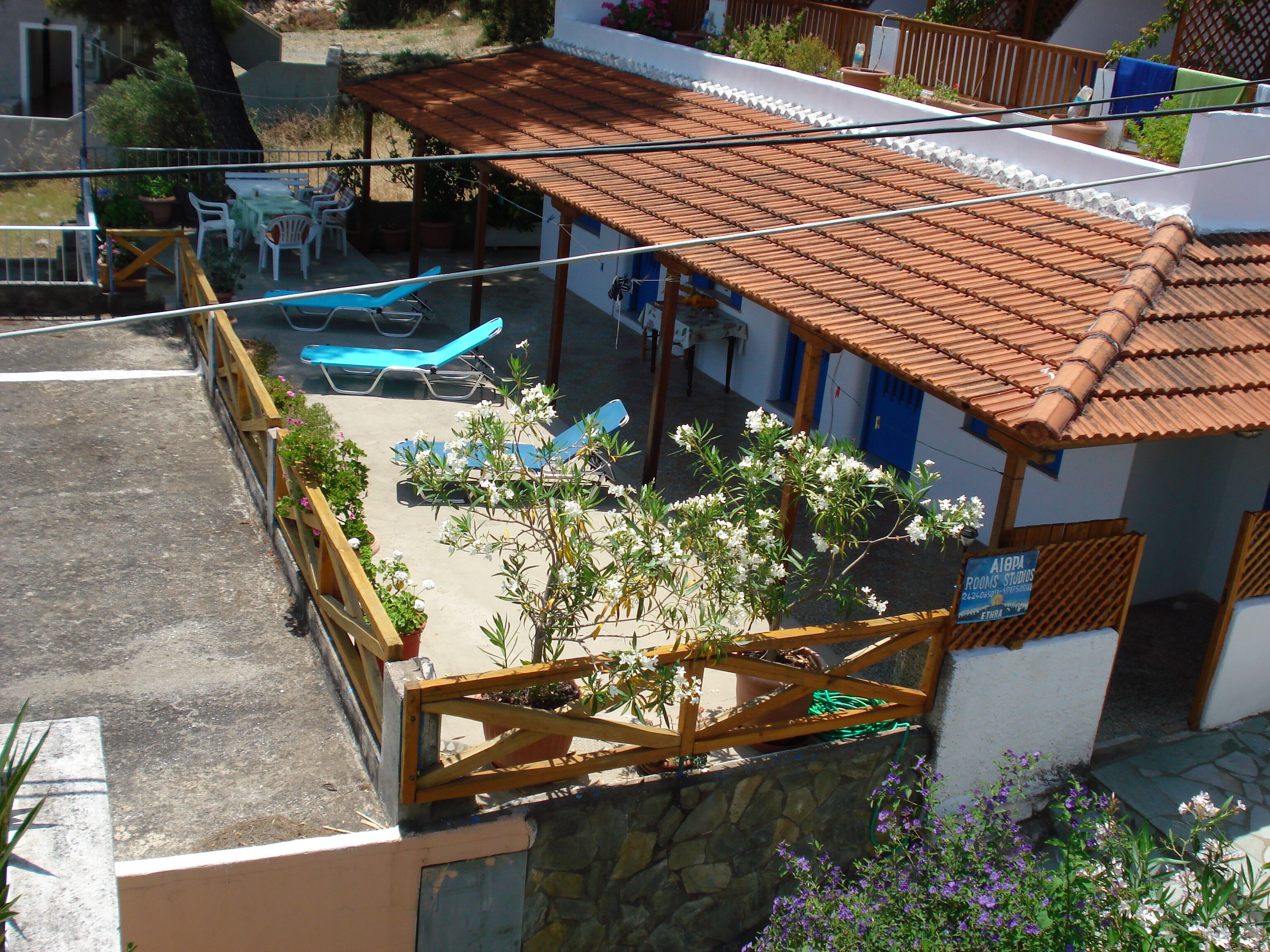A residential property with a tiled patio, outdoor seating, and a small garden area.