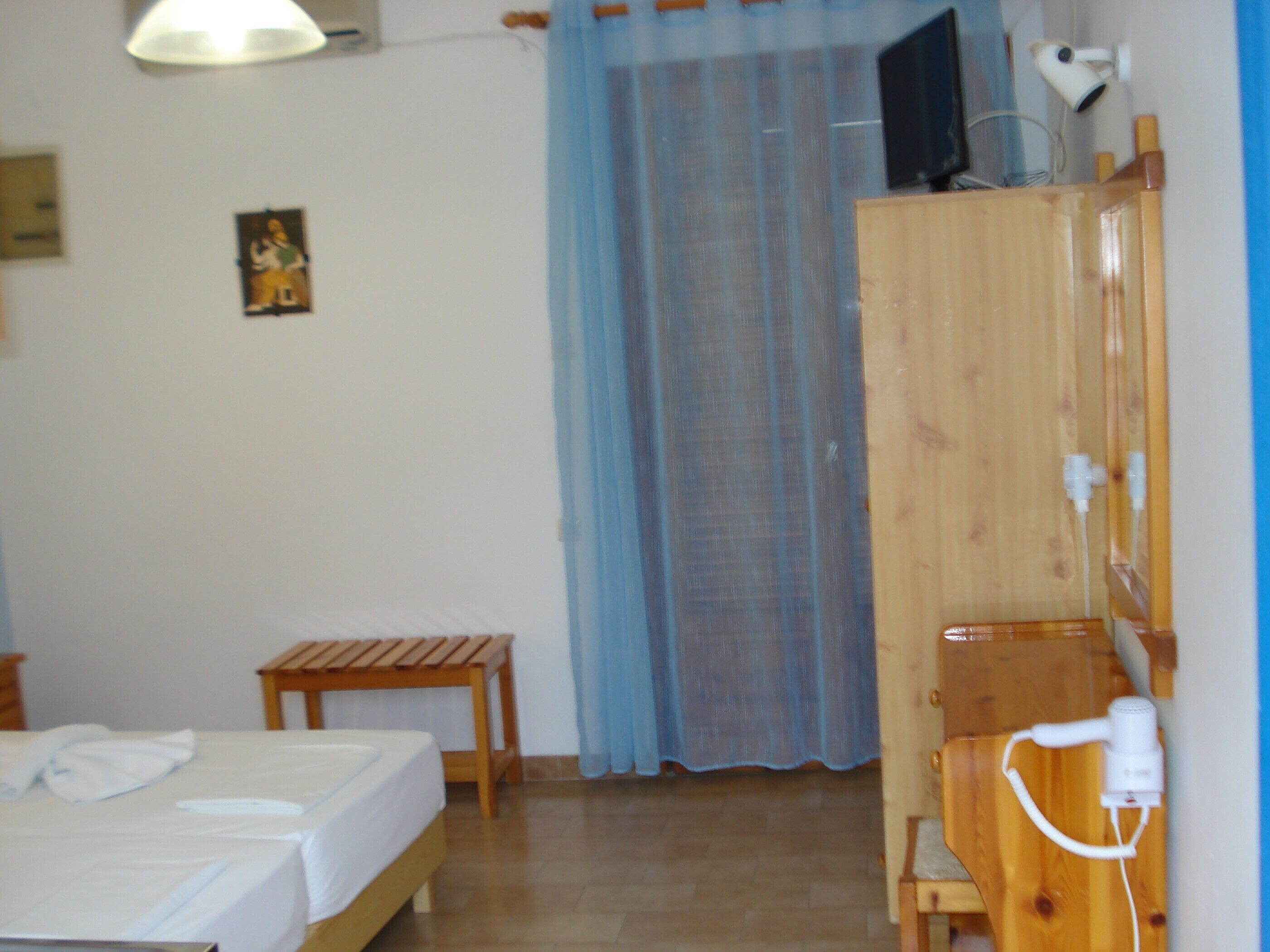A room with a bed, a small table, a wardrobe, and a hairdryer.