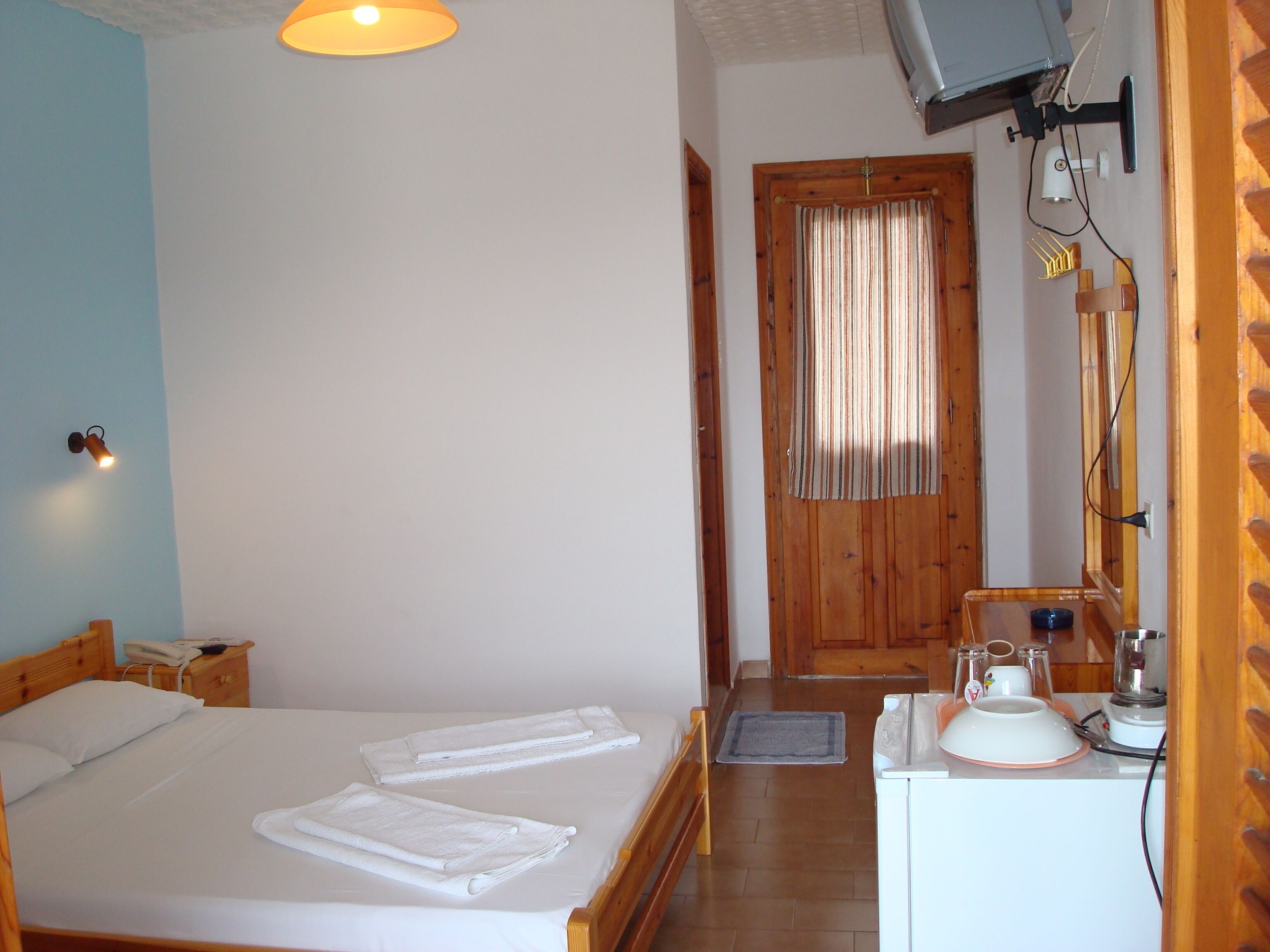 A bedroom with a bed, bedside table, lamp, and a wooden door.