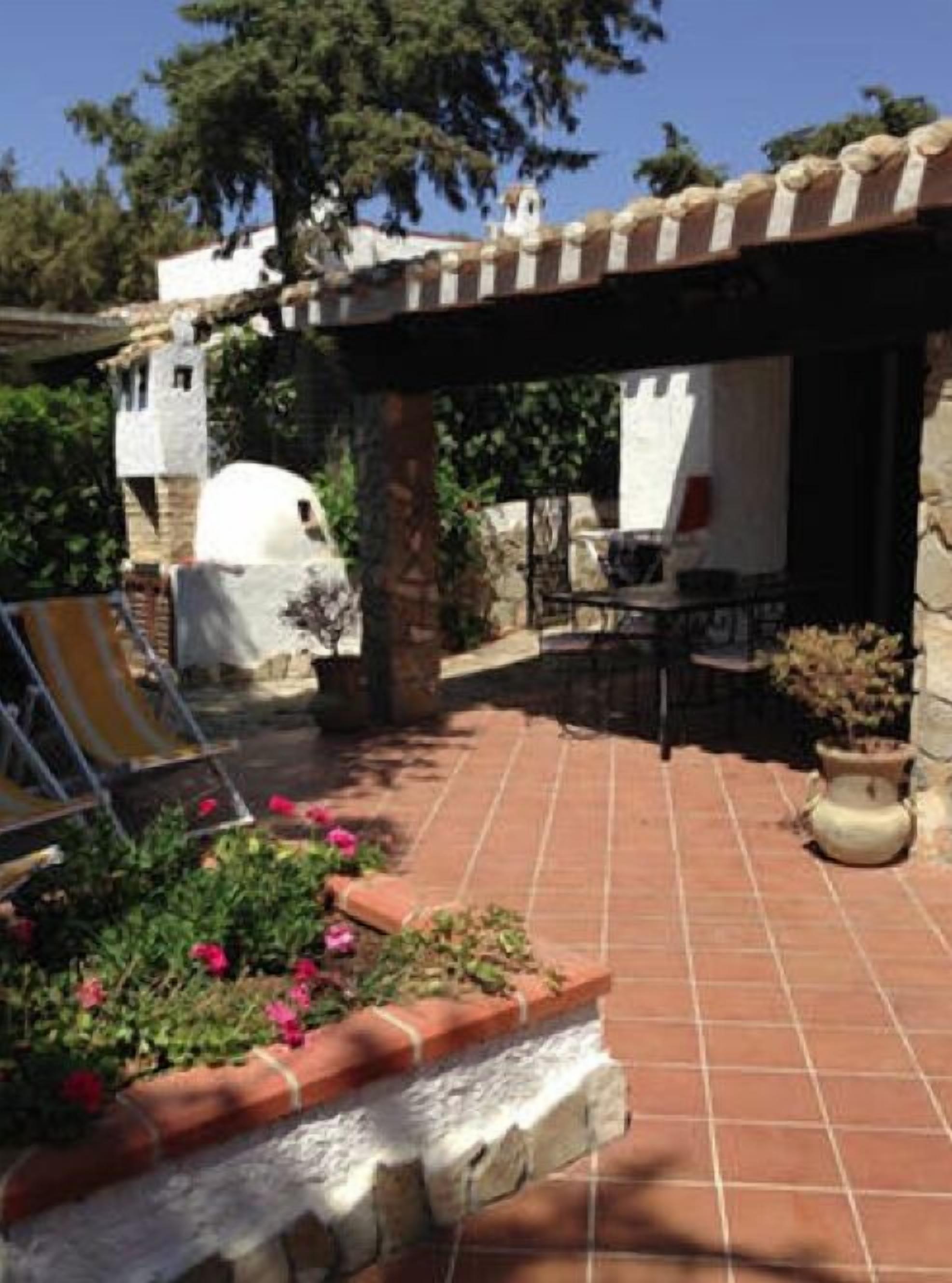 A patio with a tiled floor, a pergola, a white dome structure, and a seating area with a table and chairs.