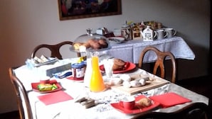 Un comedor con una mesa lista para el desayuno, con platos, tazas y una jarra de jugo de naranja.