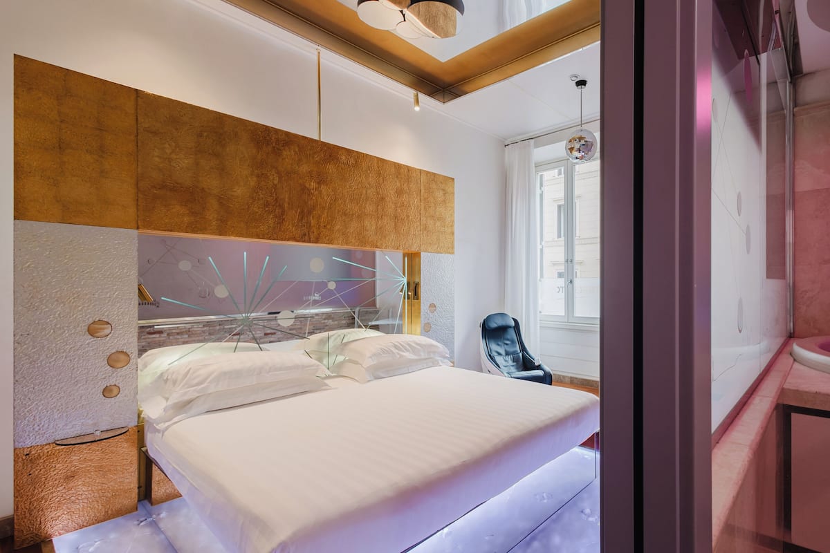 A modern bedroom with a large bed, a wooden headboard, and a glass wall.
