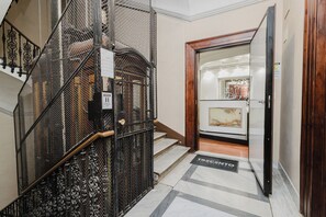A staircase with a metal railing leading to a room with a wooden door and a tiled floor.