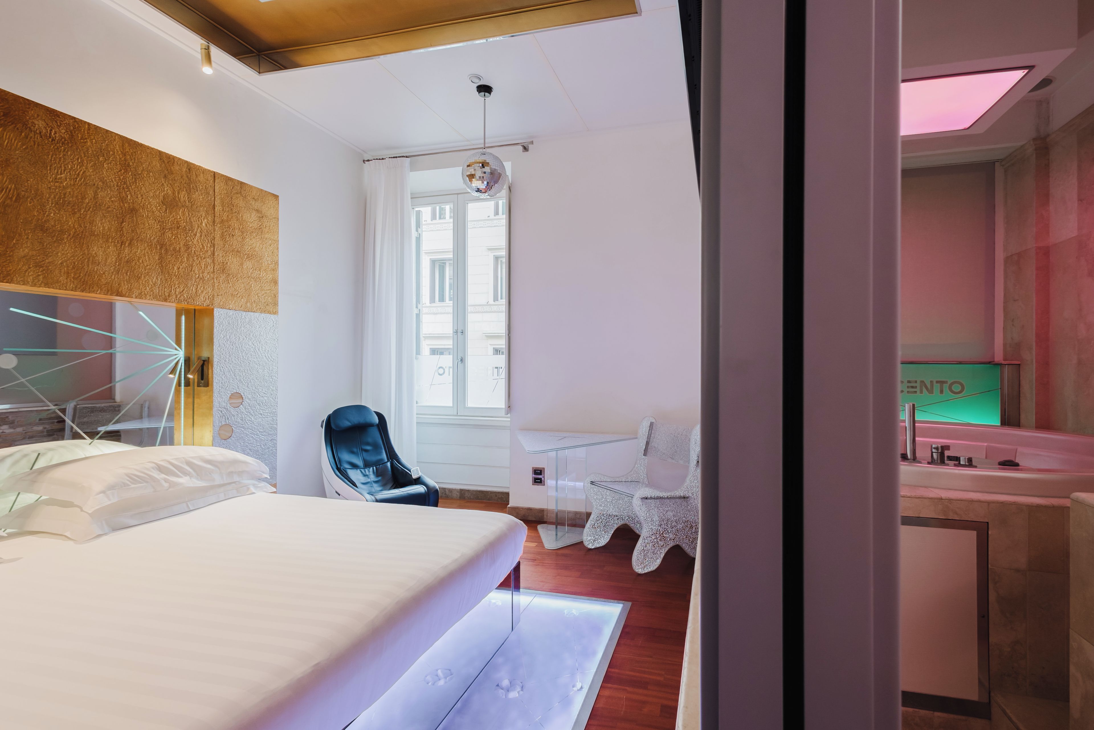 A modern hotel room with a bed, a desk, a chair, and a bathroom.