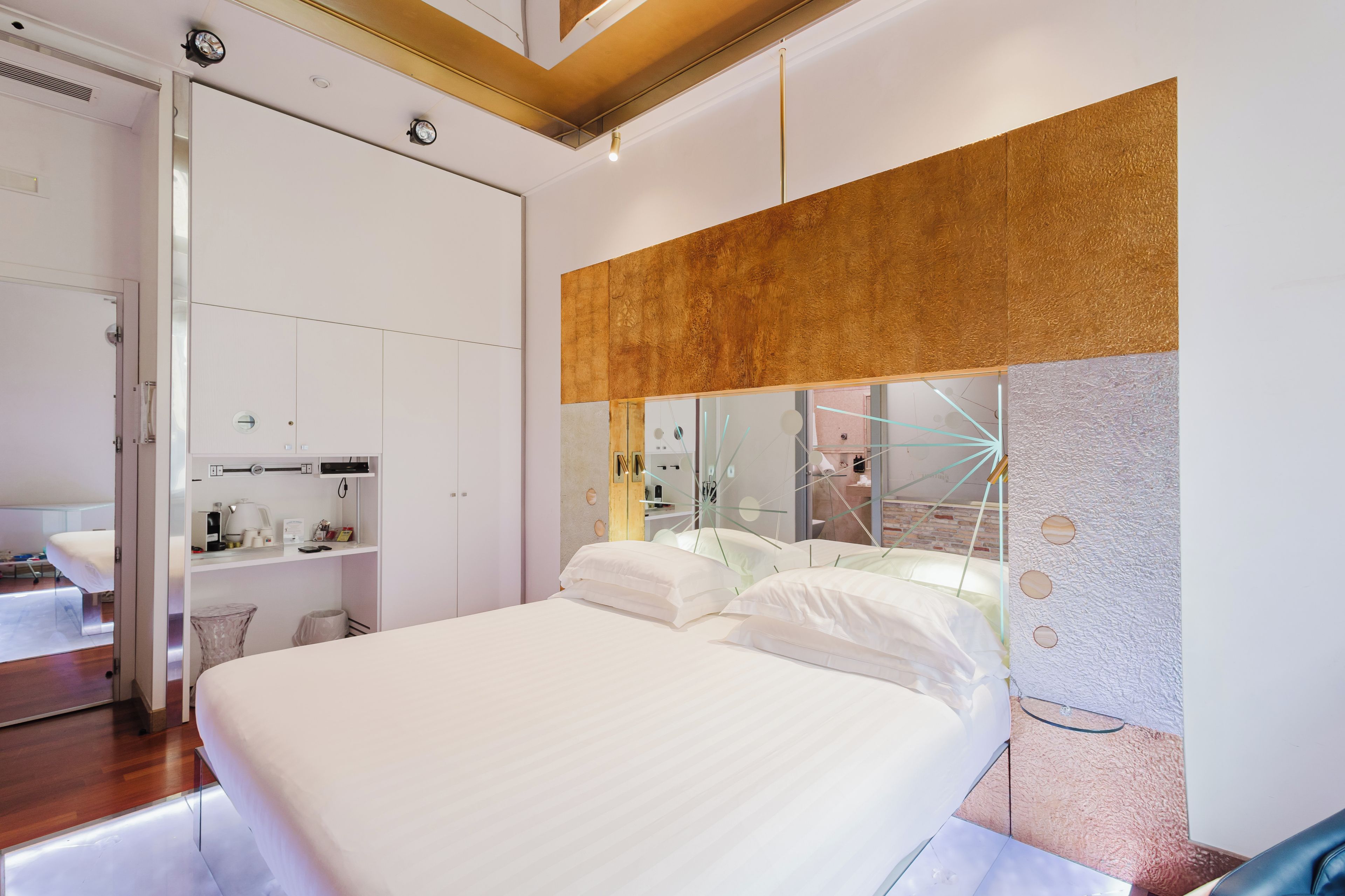 Quarto de hotel moderno com uma cama grande, um guarda-roupa embutido, uma toucador com espelho e um design de parede único.