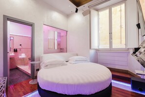 A modern bedroom with a large bed, a vanity with a mirror, and a window with blinds. - Hotel Trecento (Rome)