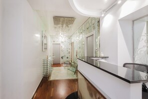 A modern kitchen with a black countertop, a glass backsplash, and a wooden floor. - Hotel Trecento (Rome)