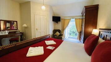 A hotel room with a bed, a desk, a chair, a television, and a window with curtains.
