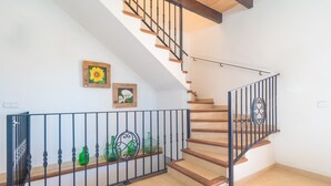 A staircase with wooden steps and black metal railings, leading to a landing with a white wall and two framed pictures. - SON PUJOL - Villa with private pool in MONTUÏRI. Free WiFi (Montuïri)