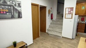 A hallway with a wooden bench, a small plant, a staircase, and a kitchen area with cabinets and a refrigerator. - Good Vibes - Lagos Guest House (Lagos)
