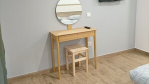 A small room with a wooden desk, a mirror, a television mounted on the wall, and a small stool. - Good Vibes - Lagos Guest House (Lagos)
