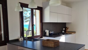 Een moderne keuken met een centraal kookeiland, witte barkrukken en hanglampen.