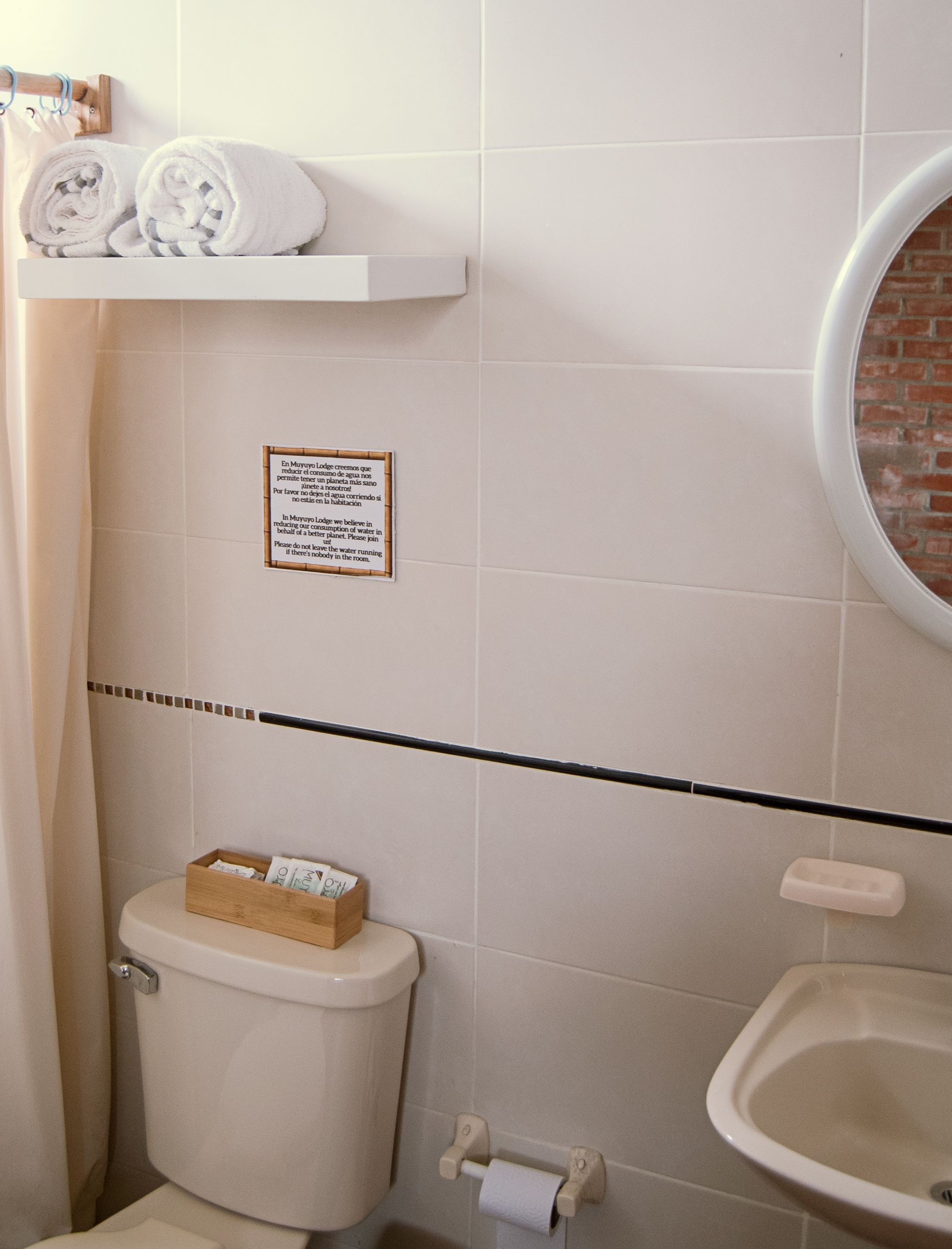 A bathroom with a toilet, a bidet, a towel rack, and a sign on the wall.