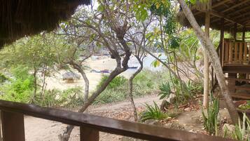 A wooden deck with a view of a beach area, including a boat and beach umbrellas.