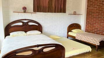 Two wooden beds with headboards, a brick wall, and a white brick wall with a window and curtain.