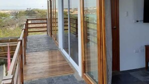 Un bâtiment moderne dot é de grandes fenêtres, d’un balcon en bois et d’un sol en pierre.