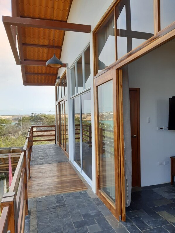 A modern building with large windows, a wooden balcony, and a flat roof. - Muyuyo Lodge (Parroquia Colonche)