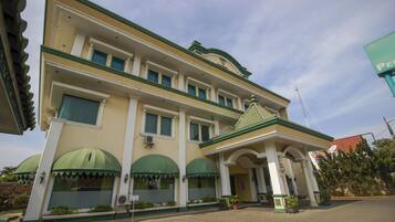 A multi-story hotel with a green and white facade, large arched windows, and a prominent entrance with columns.
