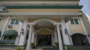 A building with a grand entrance featuring a central archway, flanked by columns, and a green awning over the entrance. - RedDoorz Plus near Alun Alun Kejaksan Cirebon (North Cirebon)