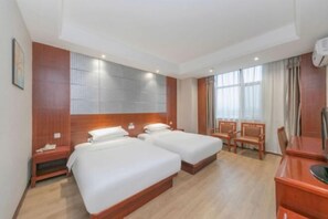 Ein Hotelzimmer mit zwei Betten, Holz-Kopfteilen, einem Schreibtisch und einem Stuhl.