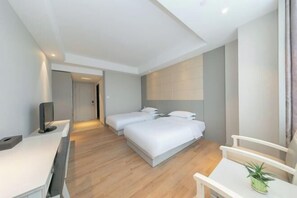 Ein modernes Hotelzimmer mit zwei Betten, einem Schreibtisch und einem Fernseher.