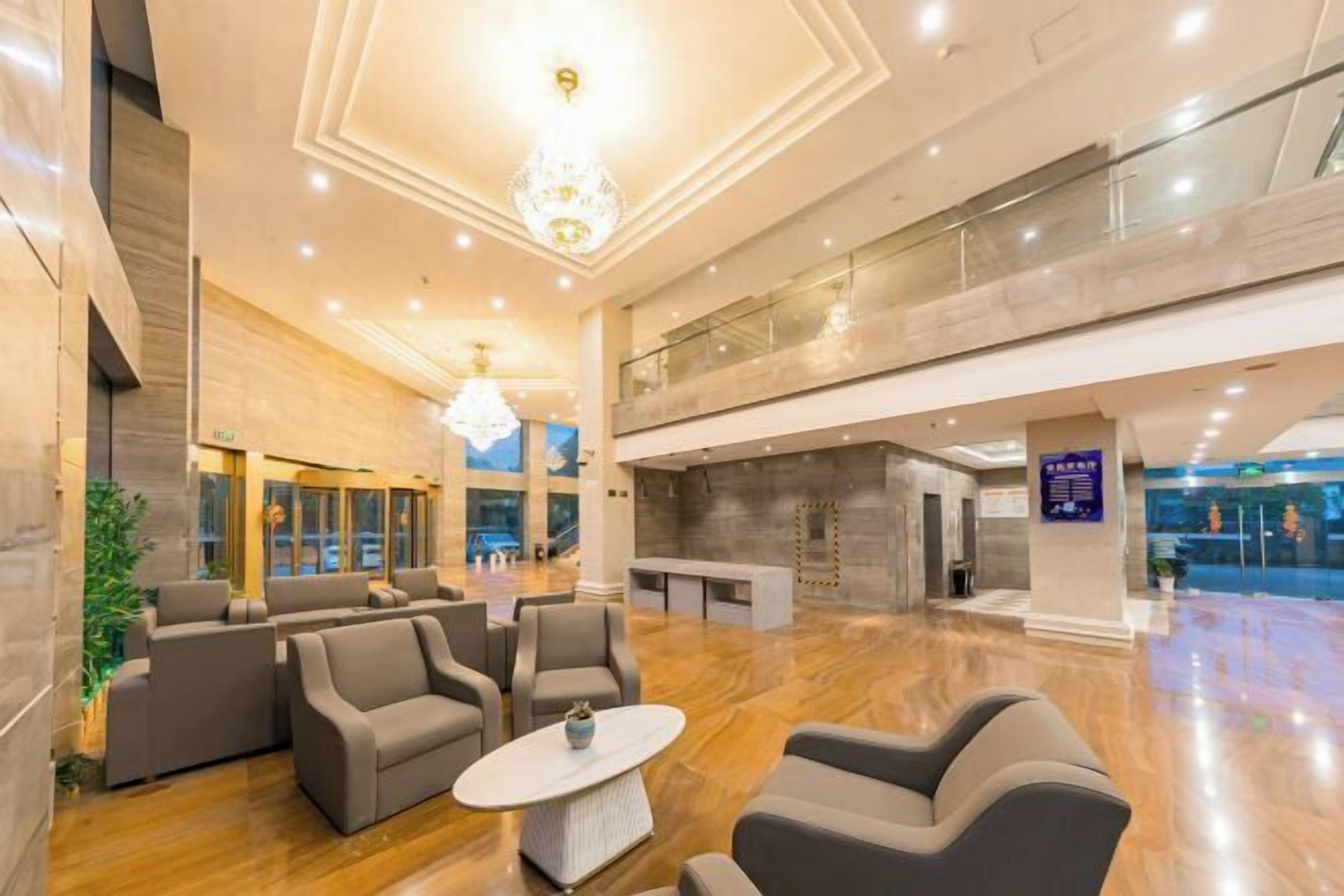 A spacious lobby with a high ceiling, a chandelier, and a seating area with sofas and a coffee table.