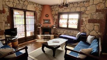 A cozy living room with stone walls, a fireplace, a television, and comfortable seating.