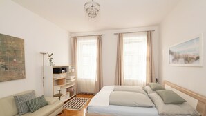A bedroom with a wooden bed, a sofa, a floor lamp, and a bookshelf.