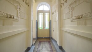 A hallway with a tiled floor, a double door with glass panels, and decorative moldings on the walls.