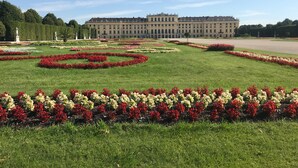 A large building with a symmetrical facade and a formal garden with geometric flower beds.