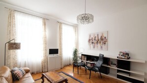 A modern living room with a sofa, coffee table, TV, and bookshelf.