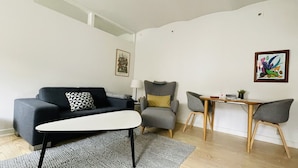 Ett modernt vardagsrum med en soffa, ett soffbord, ett matbord med stolar och en lampa.