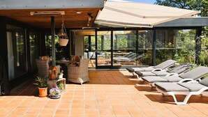 Un patio exterior moderno con sillones de descanso, una zona de comedor y plantas en macetas.
