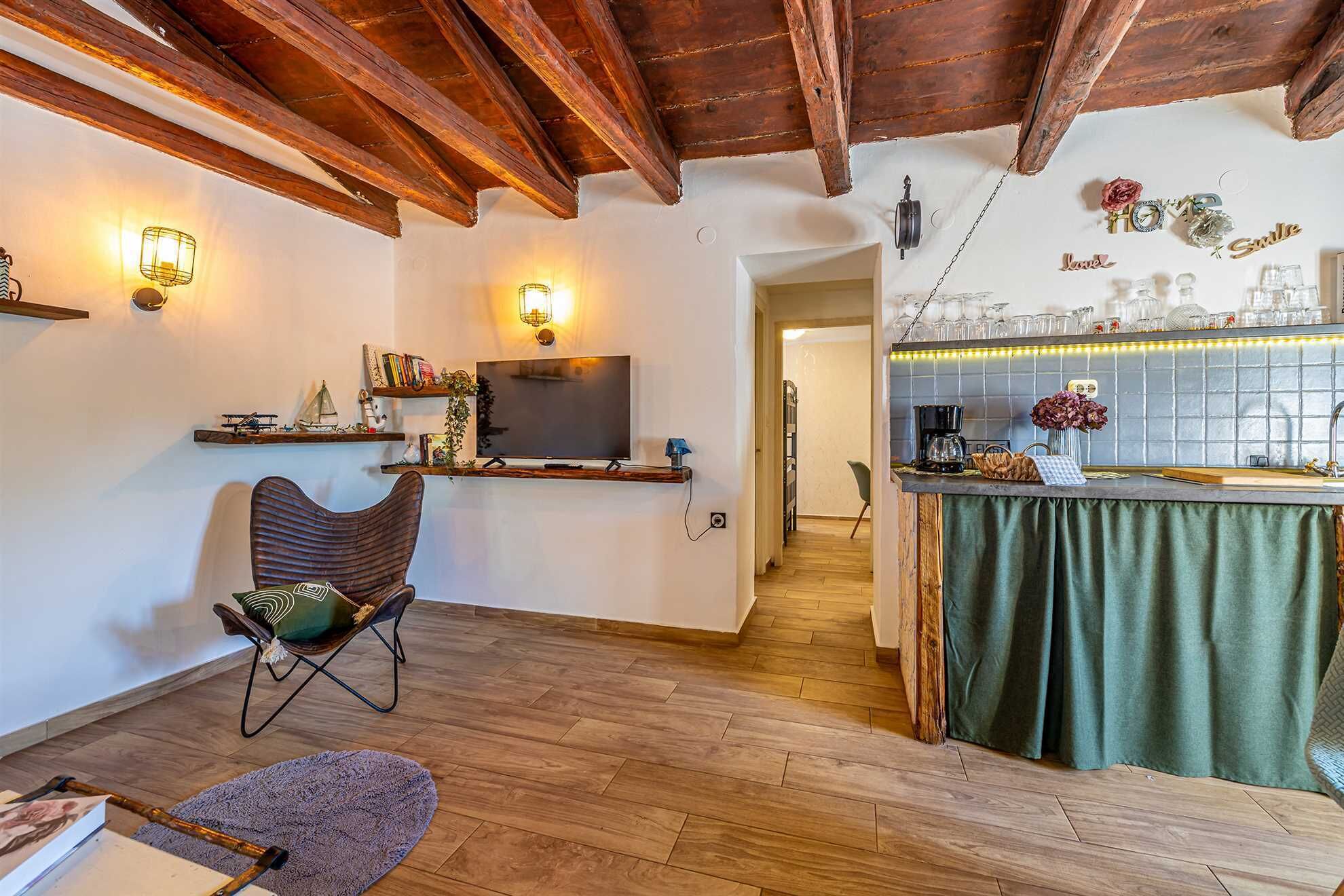 A cozy living room with a wooden ceiling, a TV, and a bar area with a green tablecloth.