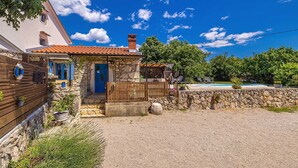 A stone house with a blue door, a wooden fence, and a gravel driveway. - Rustic holiday house DEPOPE with private pool (Skrpčići)