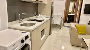 Een moderne keuken met een ingebouwde wasmachine, een zithoek met een bank en salontafel, en een aparte eettafel met stoelen.