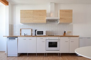 Een moderne keuken met witte kasten, een magnetron, oven en vaatwasser.