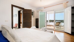 A bedroom with a bed, a chair, a wardrobe, and a balcony with a view. - Luxurious Villa with Panoramic View, Multiple Terraces and Large Pool (Costa Teguise)