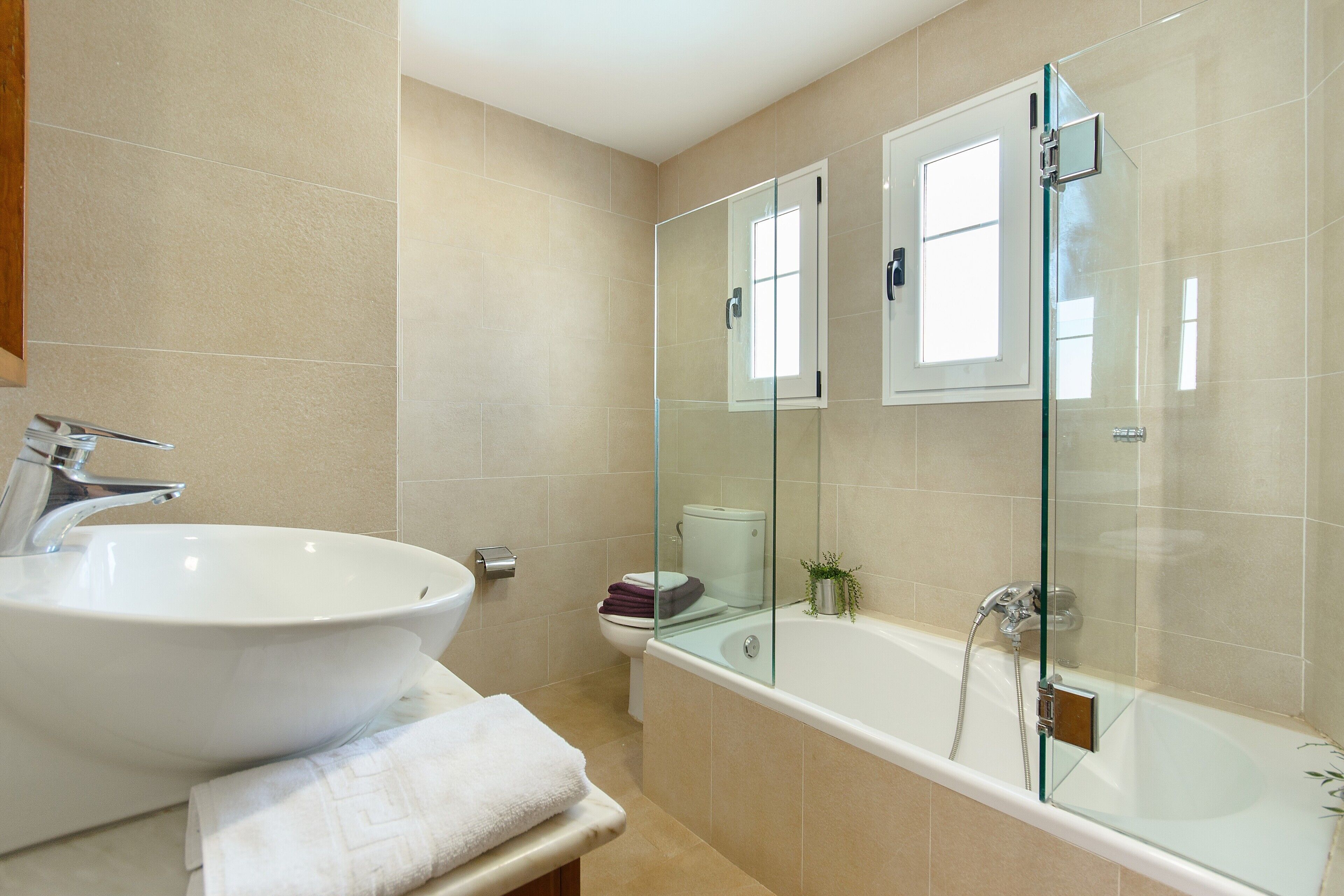 A bathroom with a large white sink, a glass-enclosed shower, and a toilet.