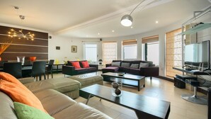 A modern living room with a sofa, coffee table, and dining area. - Luxurious Villa with Panoramic View, Multiple Terraces and Large Pool (Costa Teguise)