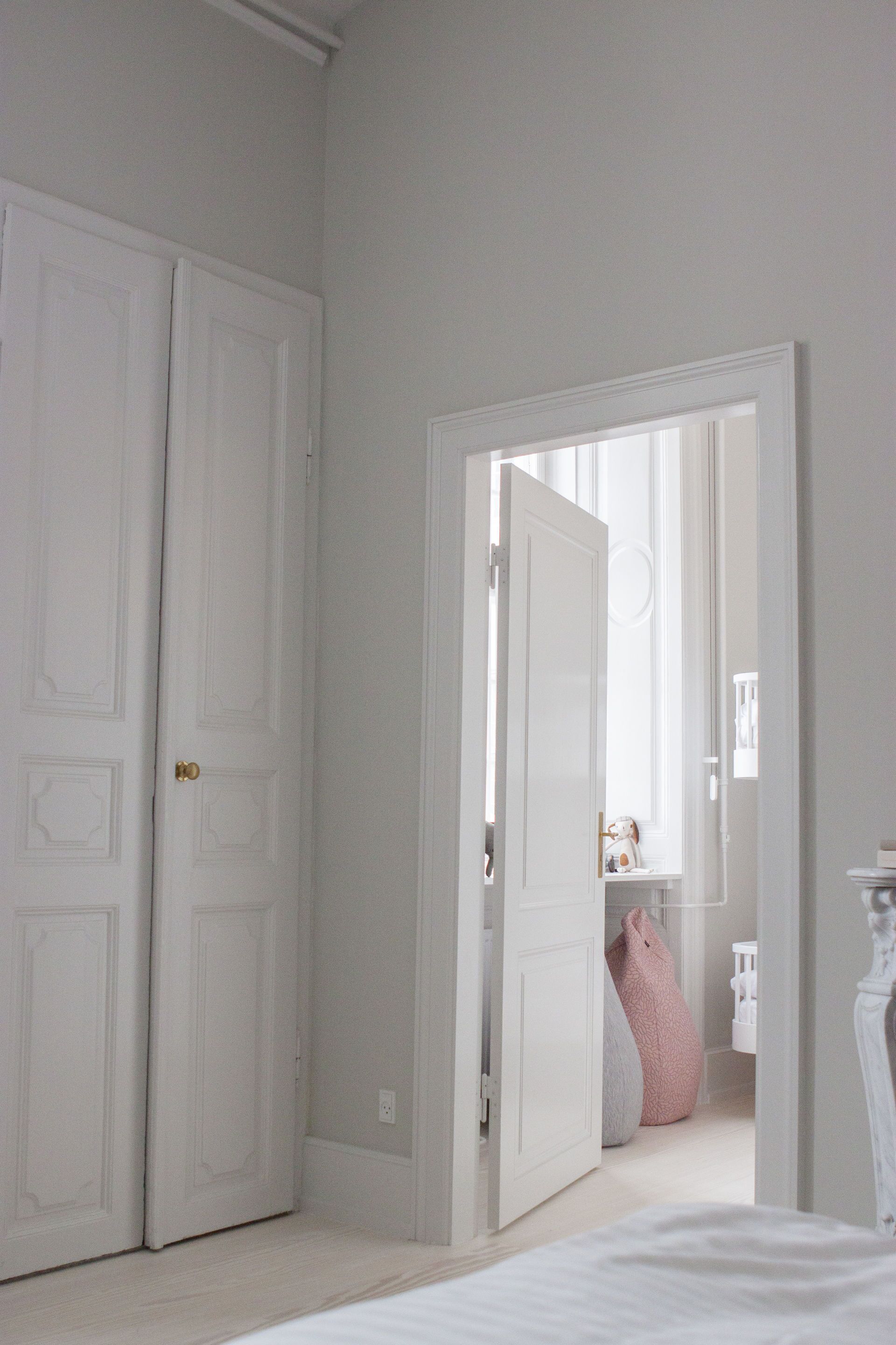 A bedroom with a bed, a white wardrobe, and a doorway leading to another room.