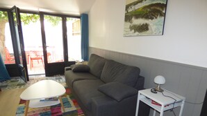 Una sala de estar con un sofá gris, una mesa de centro blanca y una alfombra colorida.