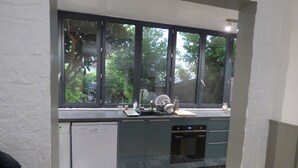 Una cocina con lavavajillas, un lavabo y ventana con vistas a un jardín.