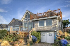 Une maison à deux étages dotée d’un balcon, d’un garage et d’un escalier en pierre menant à l’entrée.