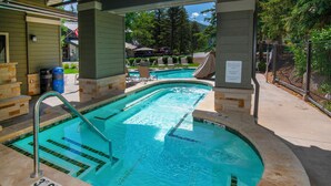 Une piscine dont la profondeur est indiquée par un repère à 36 pouces, entourée de chaises longues et dotée d’un espace abrité.