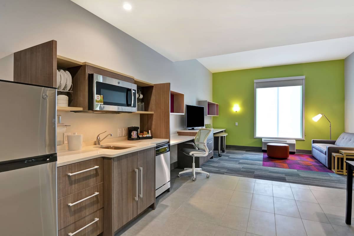 Una cocina moderna con electrodomésticos integrados, un comedor con mesa y sillas, y un amplio ventanal que proporciona luz natural.