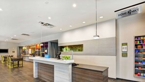 Ein Hotel-Rezeptionsbereich mit Empfangstresen, Stühlen, einem Essbereich und einem kleinen Verkaufsregal.
