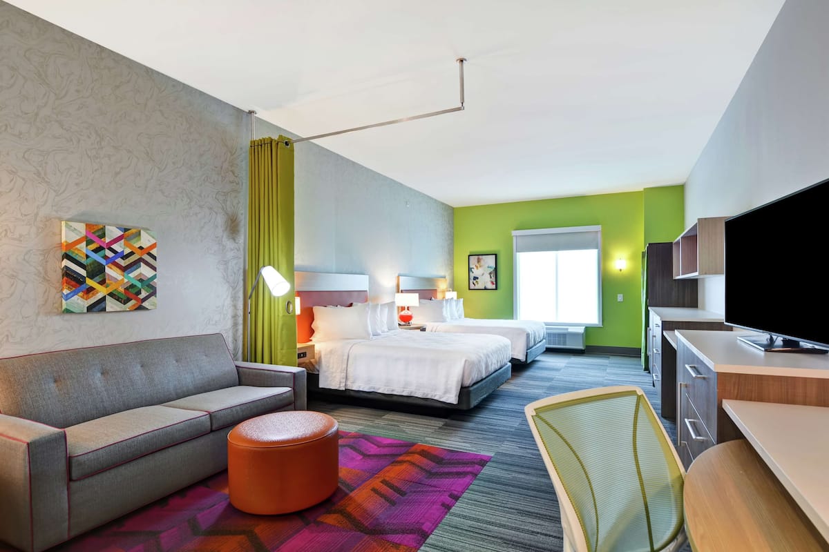 Una habitación de hotel con cama, sofá, escritorio, silla y televisión.
