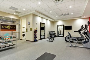 Ein Fitnessstudio mit einem Spinning-Rad, Kurzhanteln und einem Laufband.